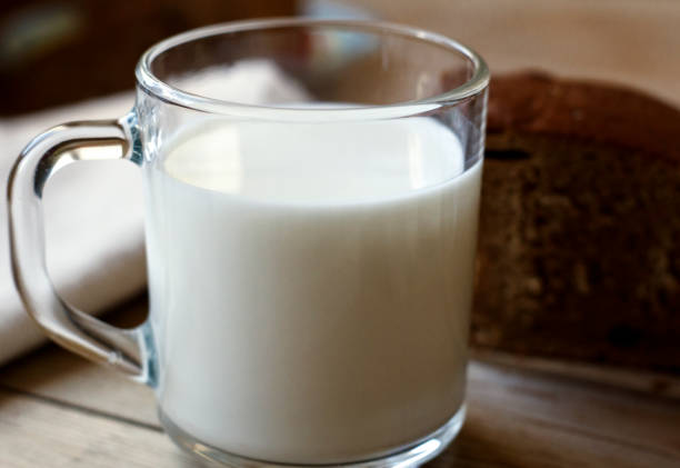 A glass of milk next to a slice of rye bread on the table